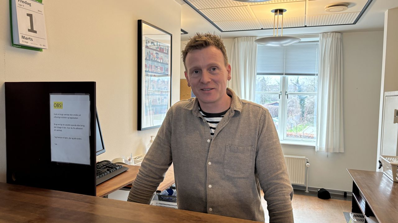 Mand står bag skranke.