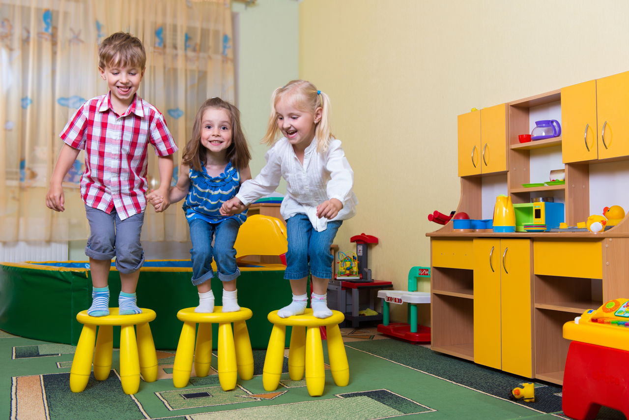 Tre børnehavebørn hopper fra hver deres skammel