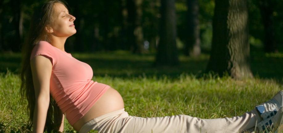Gravid Kvinde nyder solen på græsplæne